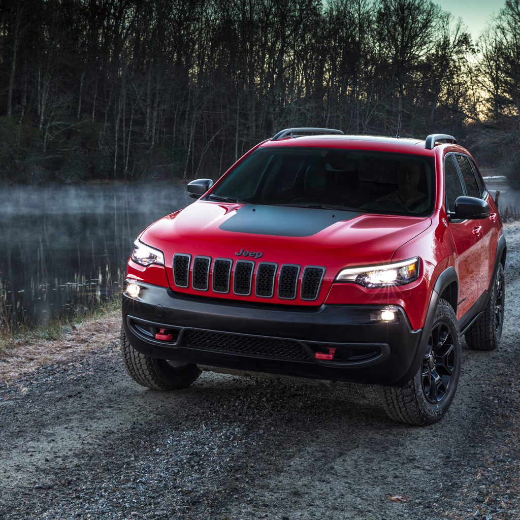 Красный автомобиль Jeep Cherokee Trailhawk, 2019 на дороге у реки