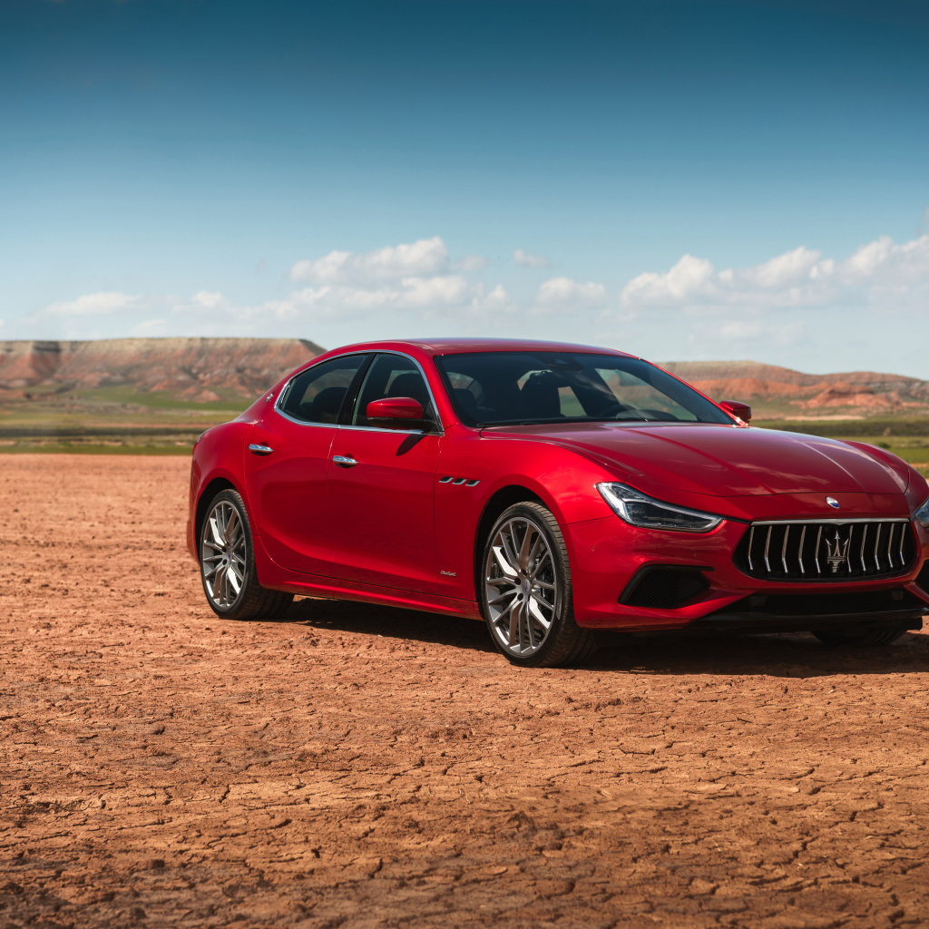 Красный автомобиль Maserati Ghibli на фоне голубого неба