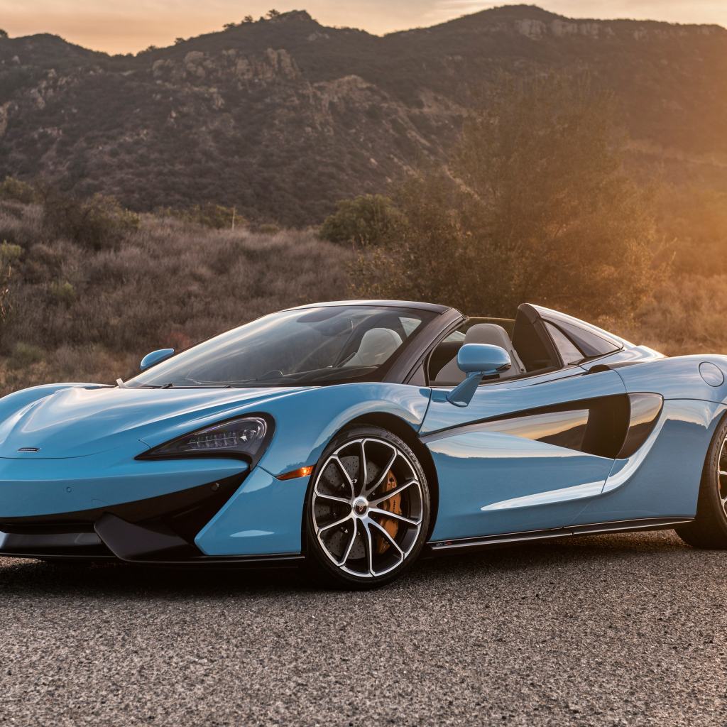 Голубой спортивный автомобиль  McLaren 570S Spider, 2018 на фоне солнца
