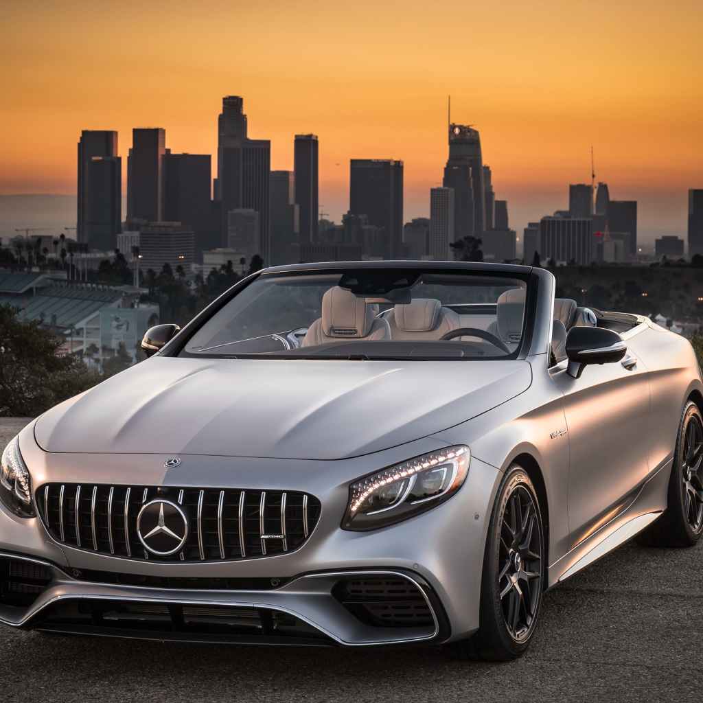 Серебристый автомобиль Mercedes AMG S63 4MATIC Cabriolet, 2018 на фоне мегаполиса