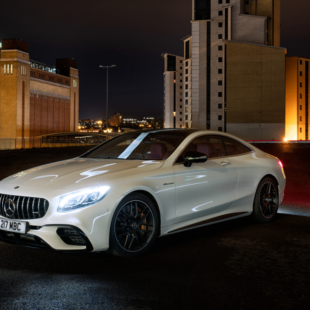 Белый автомобиль Mercedes AMG S 63 4MATIC Coupe, 2018 года на фоне города