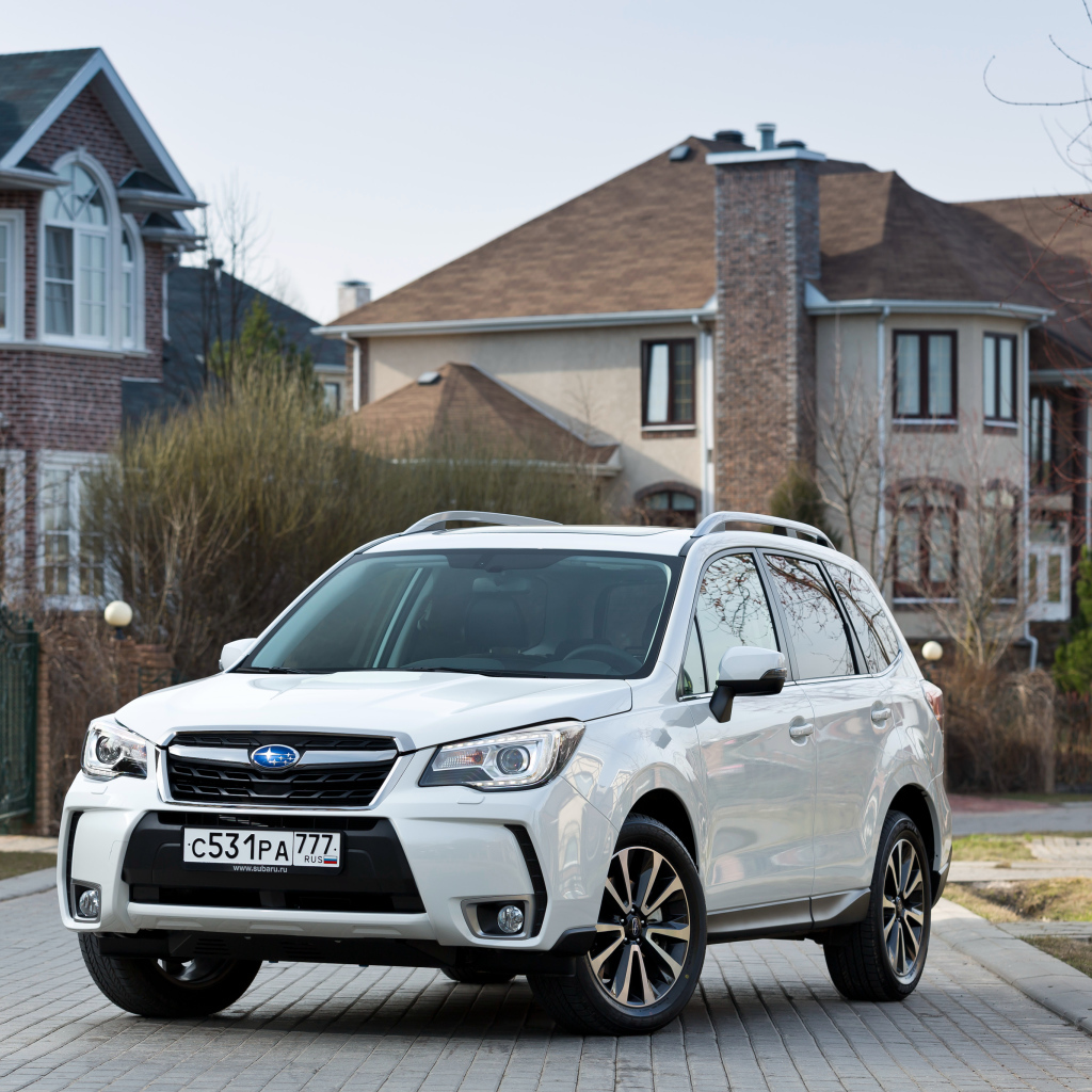 Белый автомобиль Subaru  Forester на улице у домов