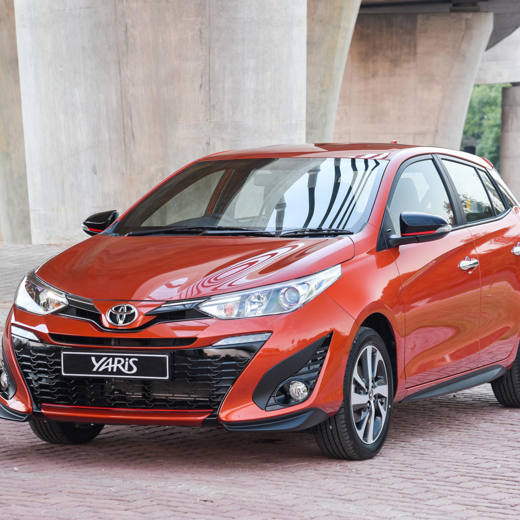 Красный автомобиль Toyota Yaris под мостом 