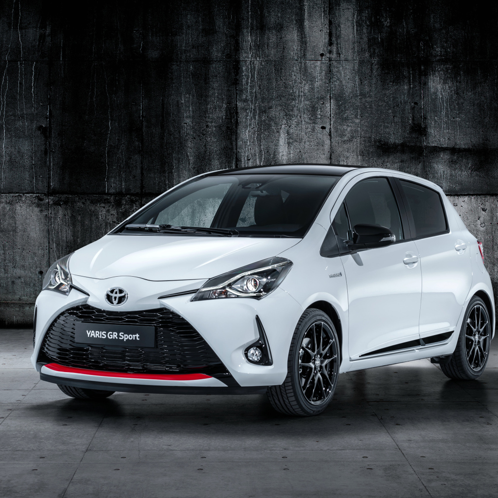 Белый автомобиль Toyota Yaris на сером фоне 