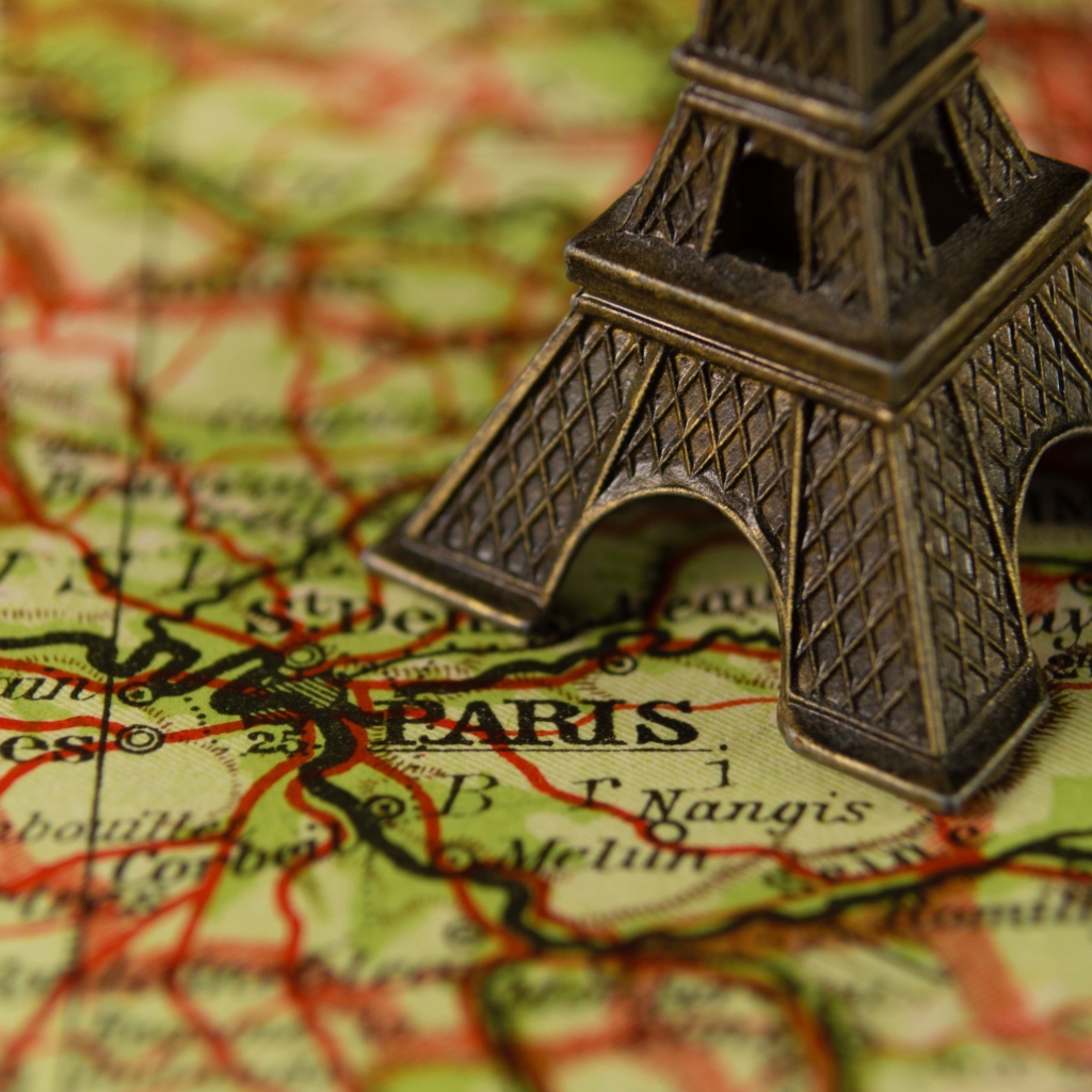 Маленькая статуэтка Эйфелева башня стоит на карте