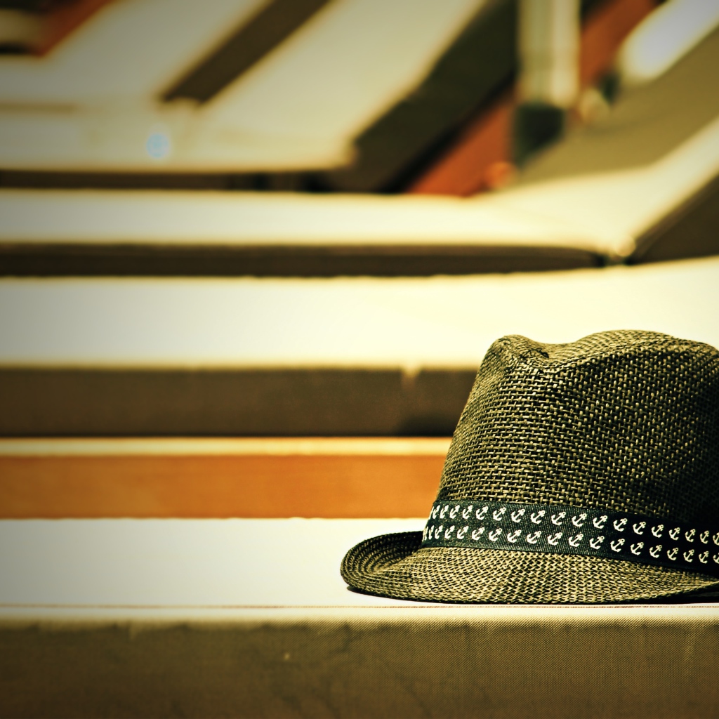 Летняя шляпа лежит на лавке в лучах солнца