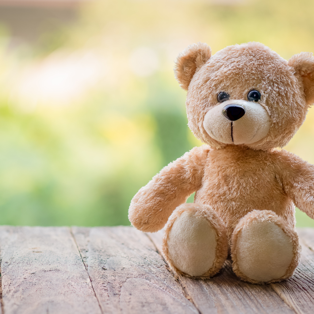 Плюшевый медведь сидит на деревянных досках