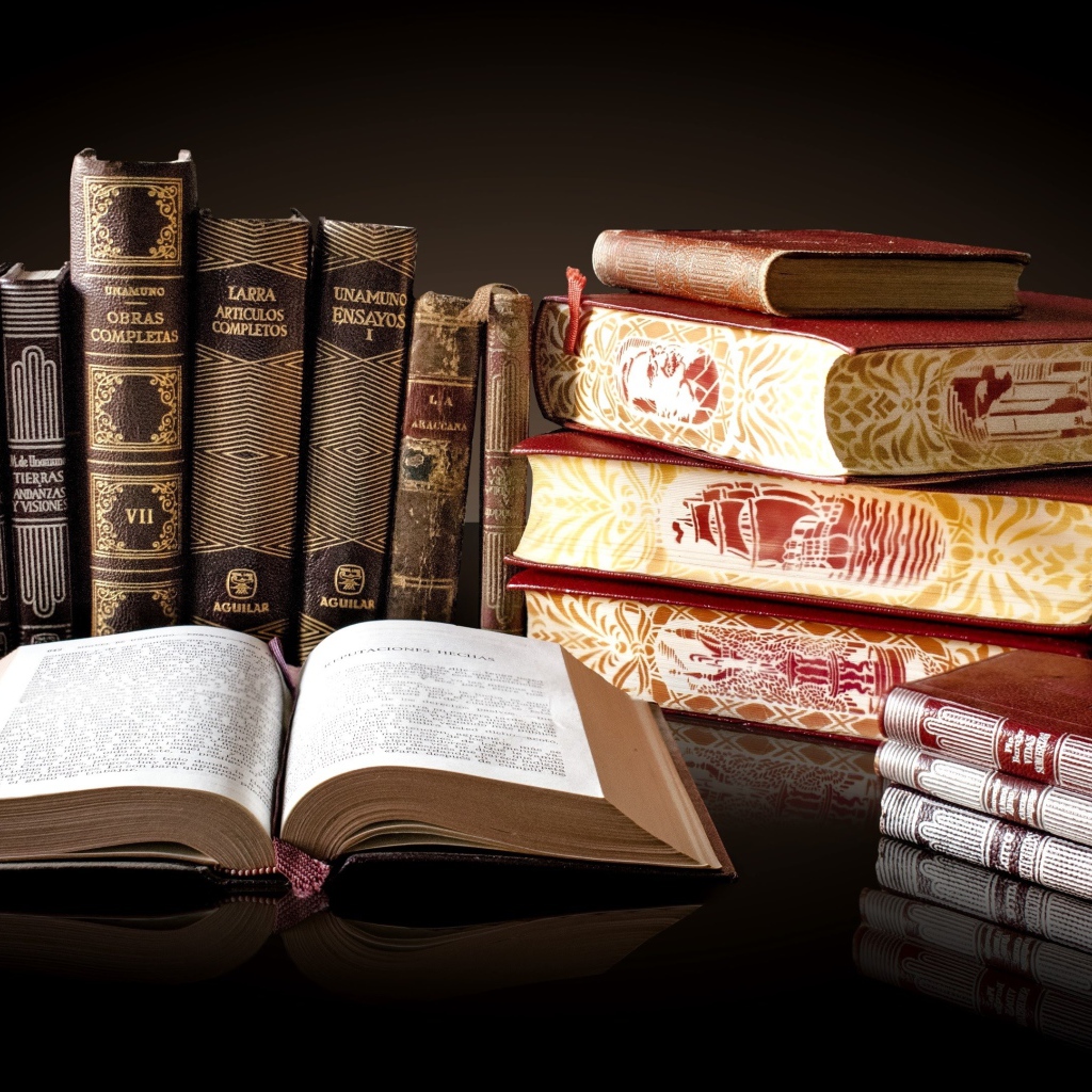 Красивые книги отражаются в зеркальной поверхности стола