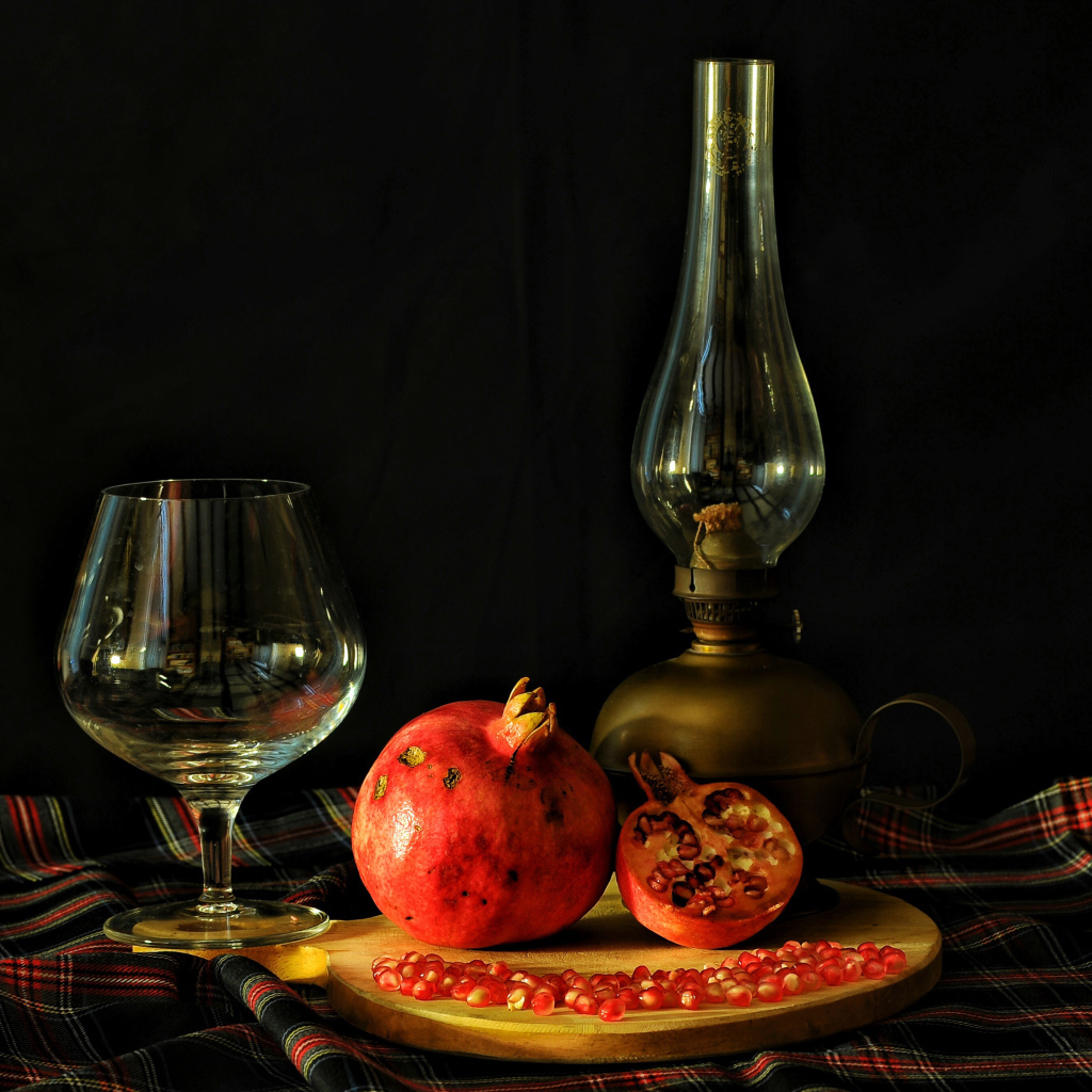 Керосиновая лампа, гранат и бокал на черном фоне