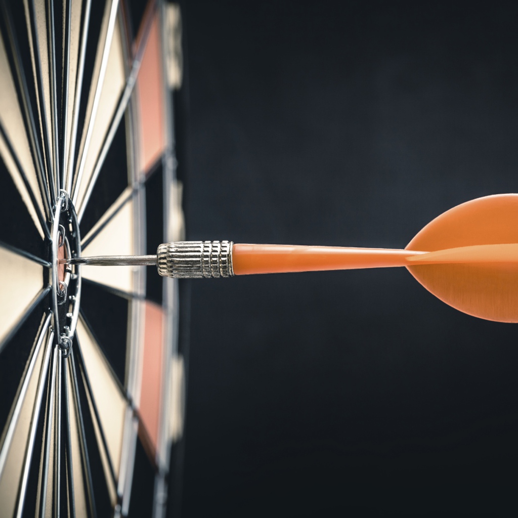 Оранжевый дротик в доске для дартса 