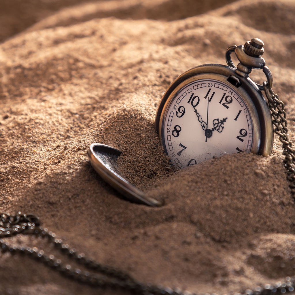 Карманные часы на цепочке в песке 