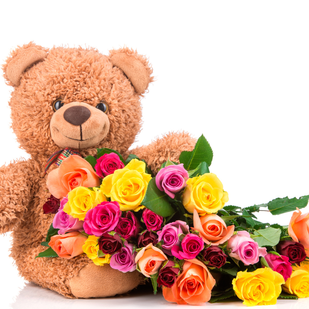 Плюшевый медведь с букетом разноцветных роз на белом фоне
