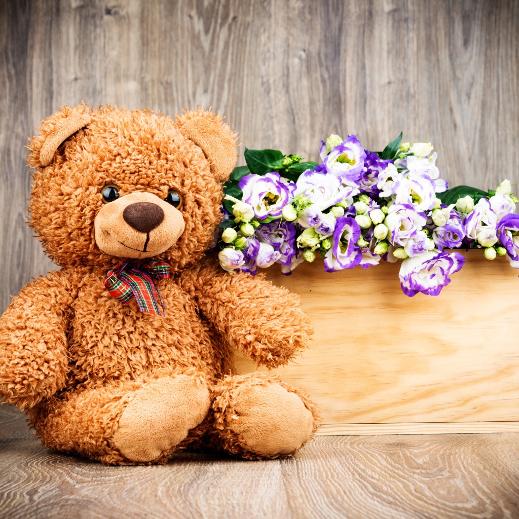 Плюшевый мишка с букетом цветов на деревянном фоне