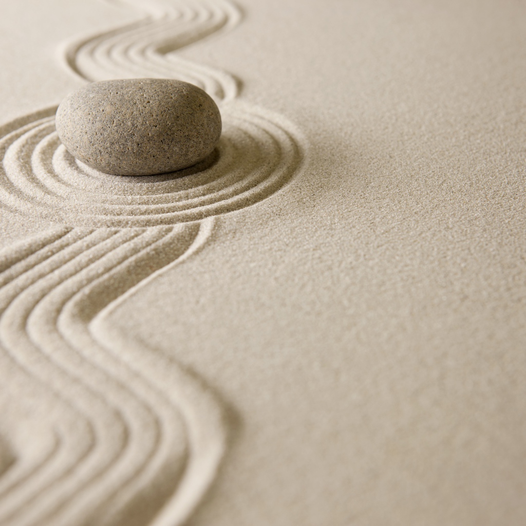 Камень лежит на рисунке на песке, дзен