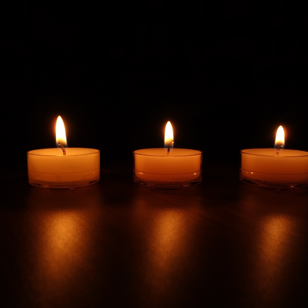 Три зажженные свечи на черном фоне