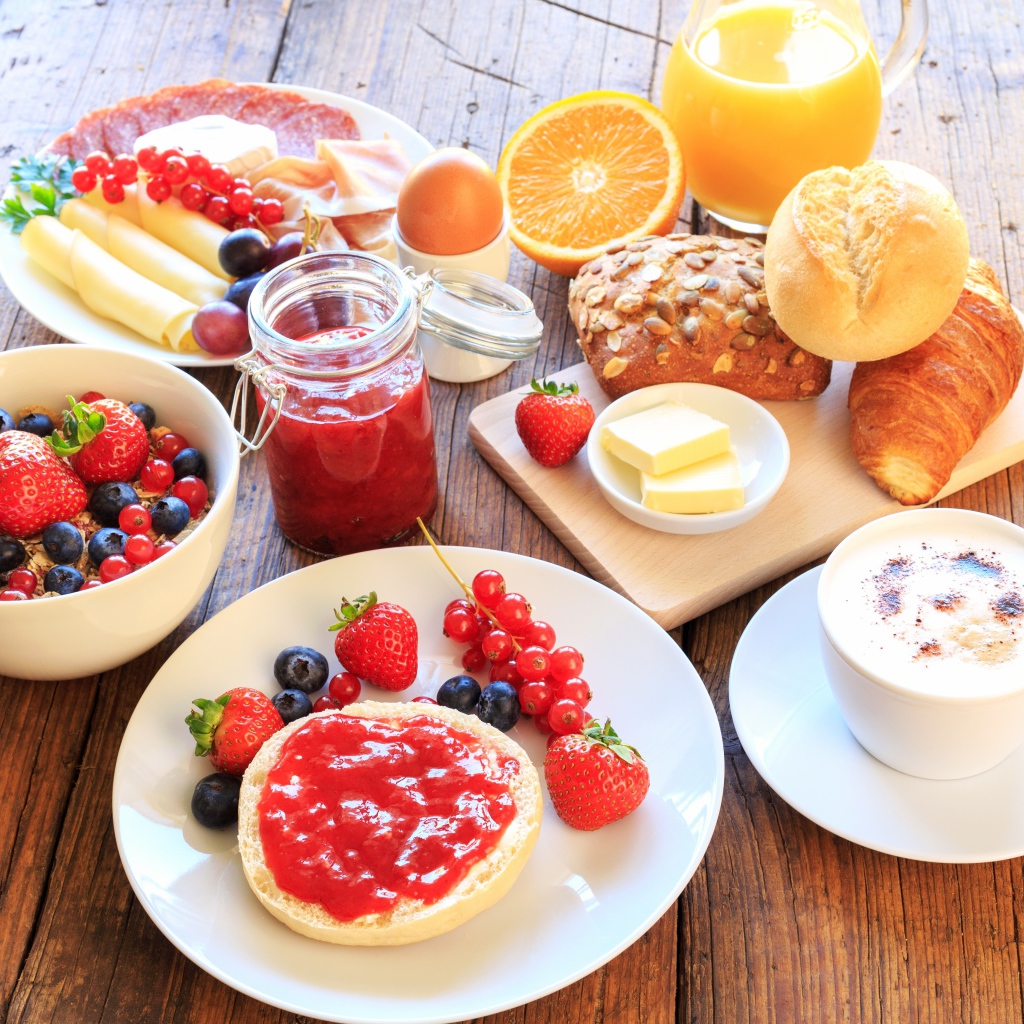 Аппетитный завтрак на столе с бутербродами, кофе и ягодами