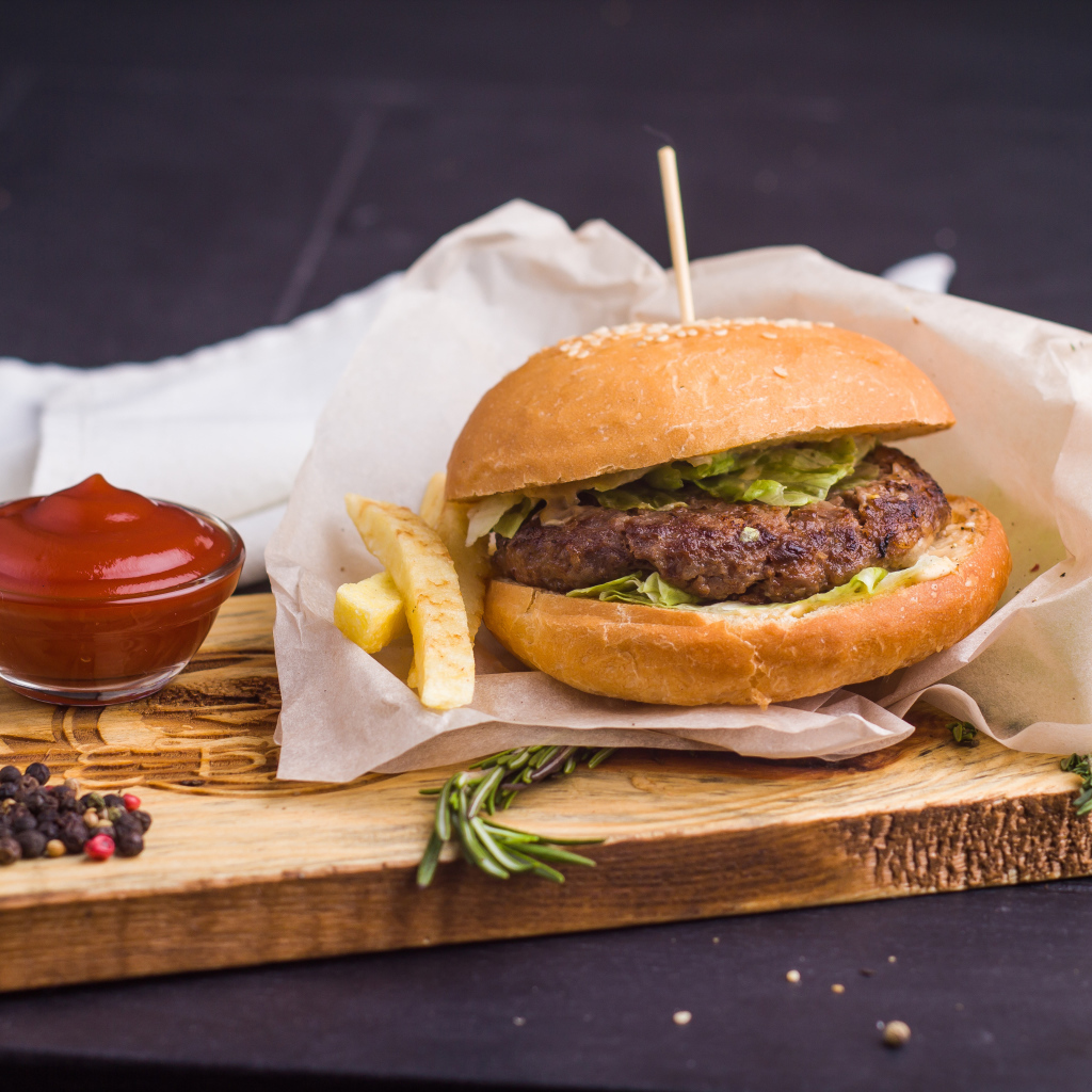 Аппетитный гамбургер с картофелем фри и кетчупом на столе