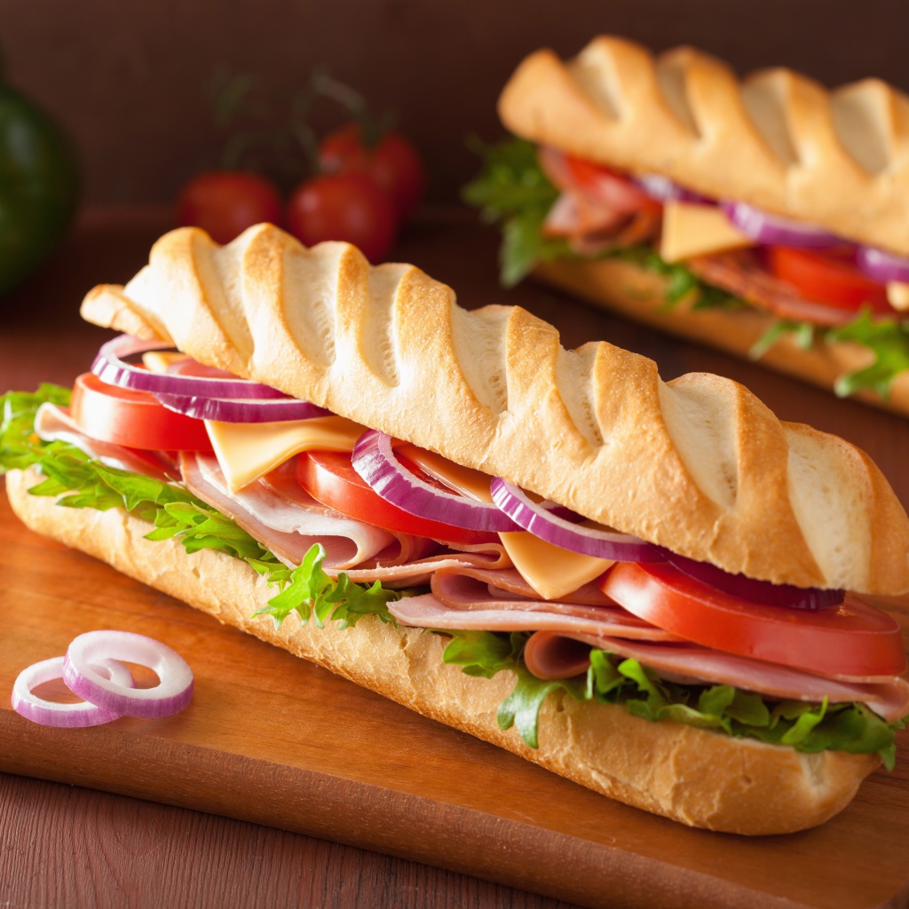 Аппетитный сэндвич с ветчиной, листьями салата, помидорами и луком