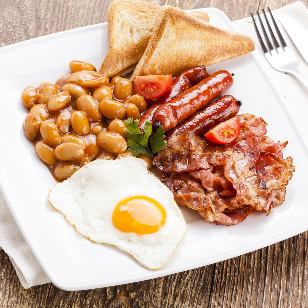 Бекон, яичница, фасоль и сосиски на тарелке к завтраку 