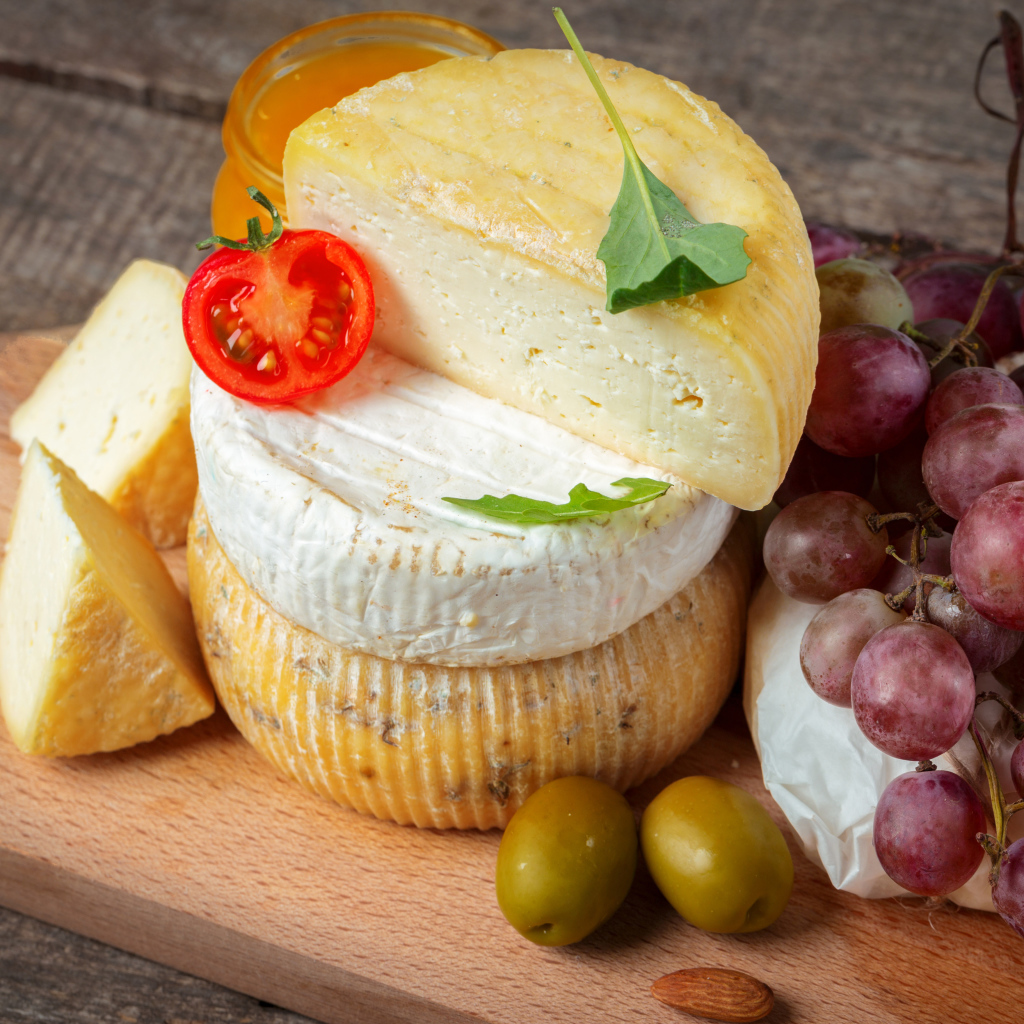 Сыр на разделочной доске с виноградом и оливками