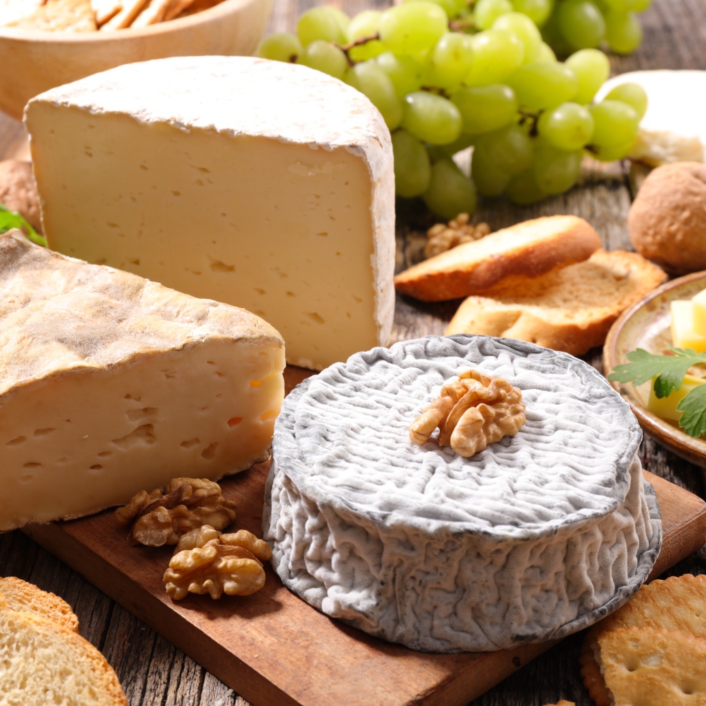 Сыр с плесенью на столе с виноградом, орехами и хлебом