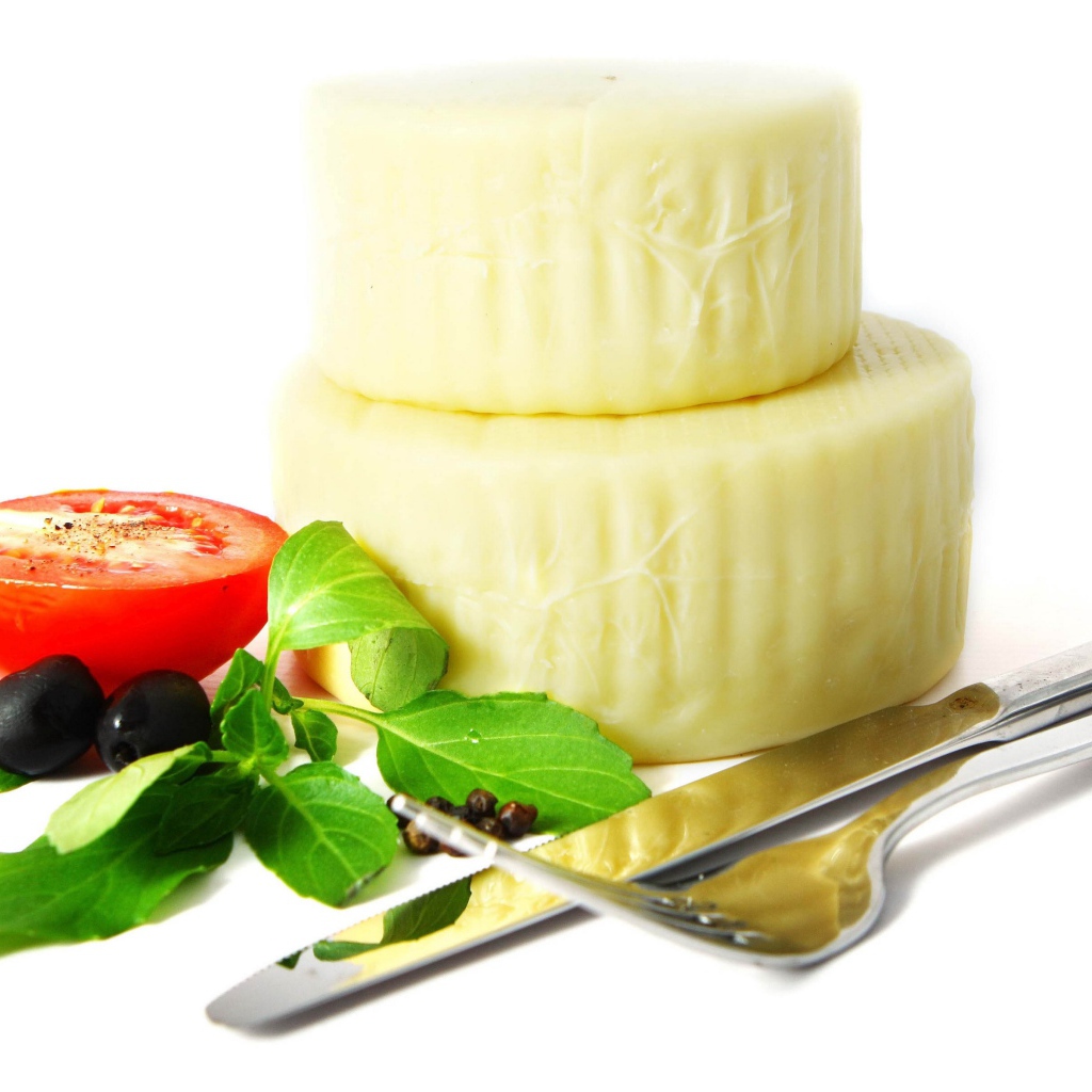 Сыр с помидором, столовыми приборами, оливками и зеленью на белом фоне