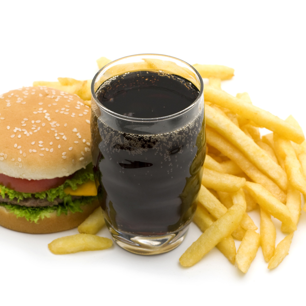 Кола в стакане на столе гамбургером и картофелем фри на белом фоне