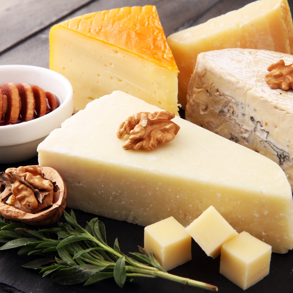Разные виды сыра на столе с медом и грецкими орехами