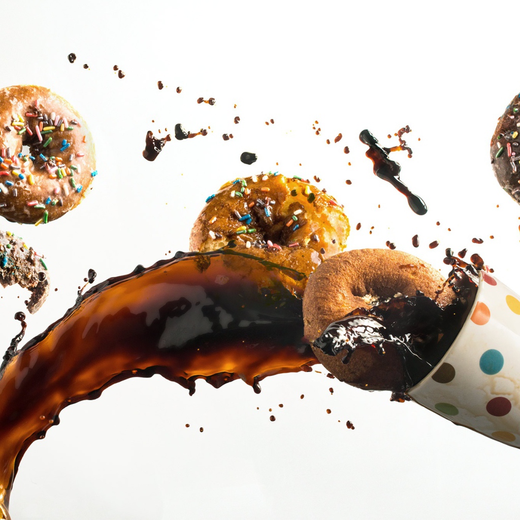 Пончики с чашкой кофе на белом фоне