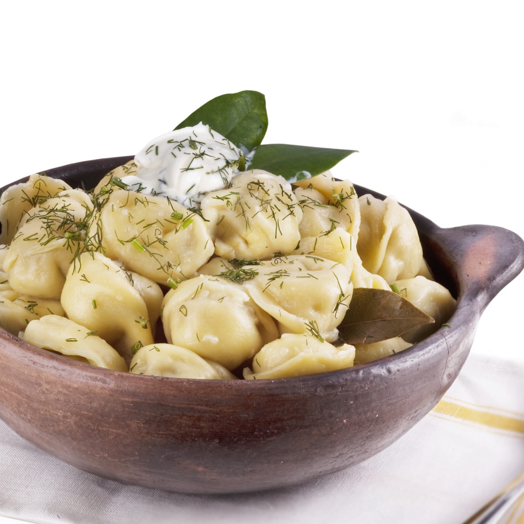 Пельмени в миске на белом фоне с ложкой 