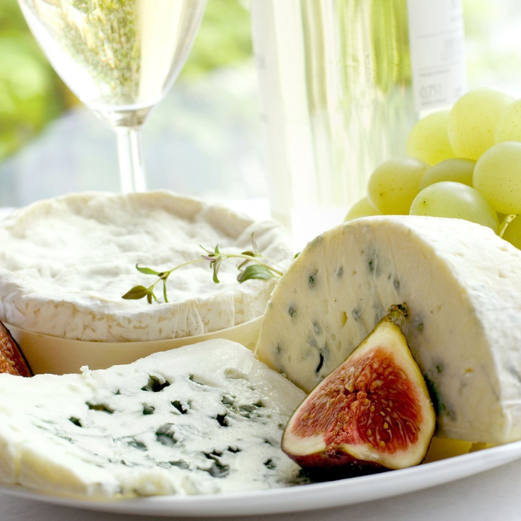 Дорогой сыр с плесенью на тарелке с инжиром и белым виноградом