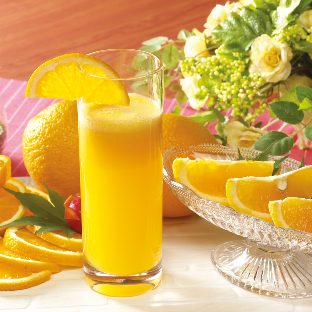 Fresh orange juice on the table with fruits and flowers