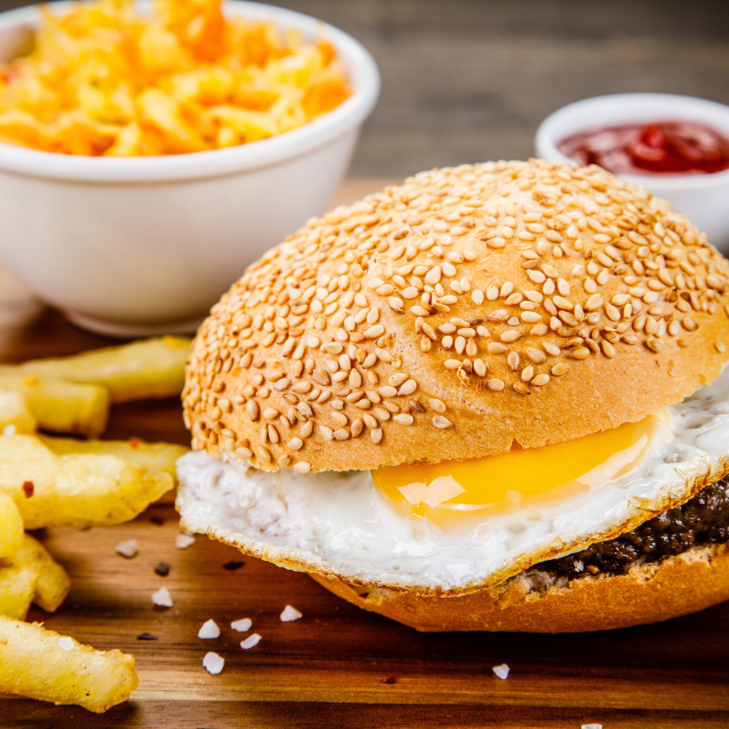 Гамбургер с яичницей на столе с картофелем фри и соусом