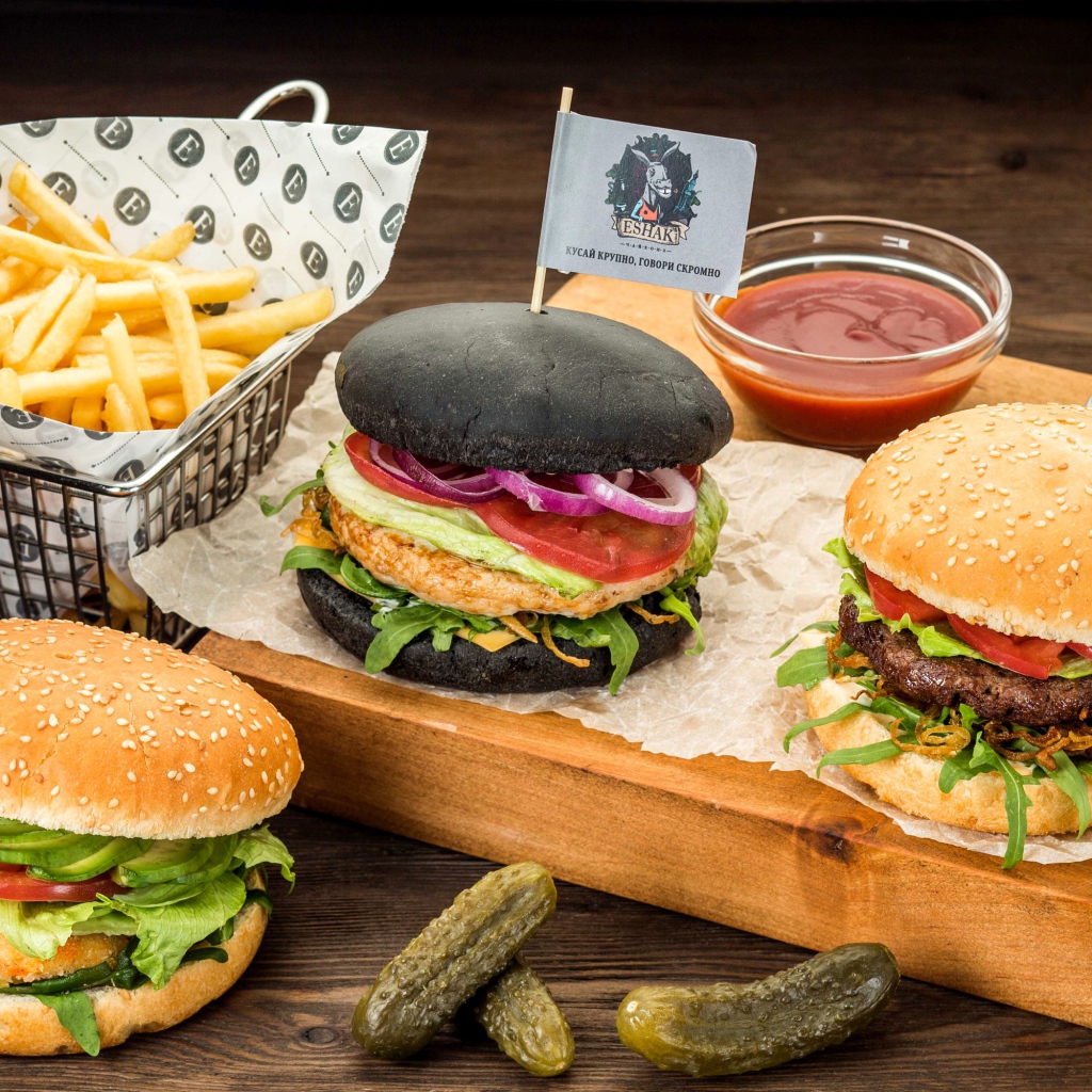 Гамбургеры с картофелем фри и солеными огурцами на столе 