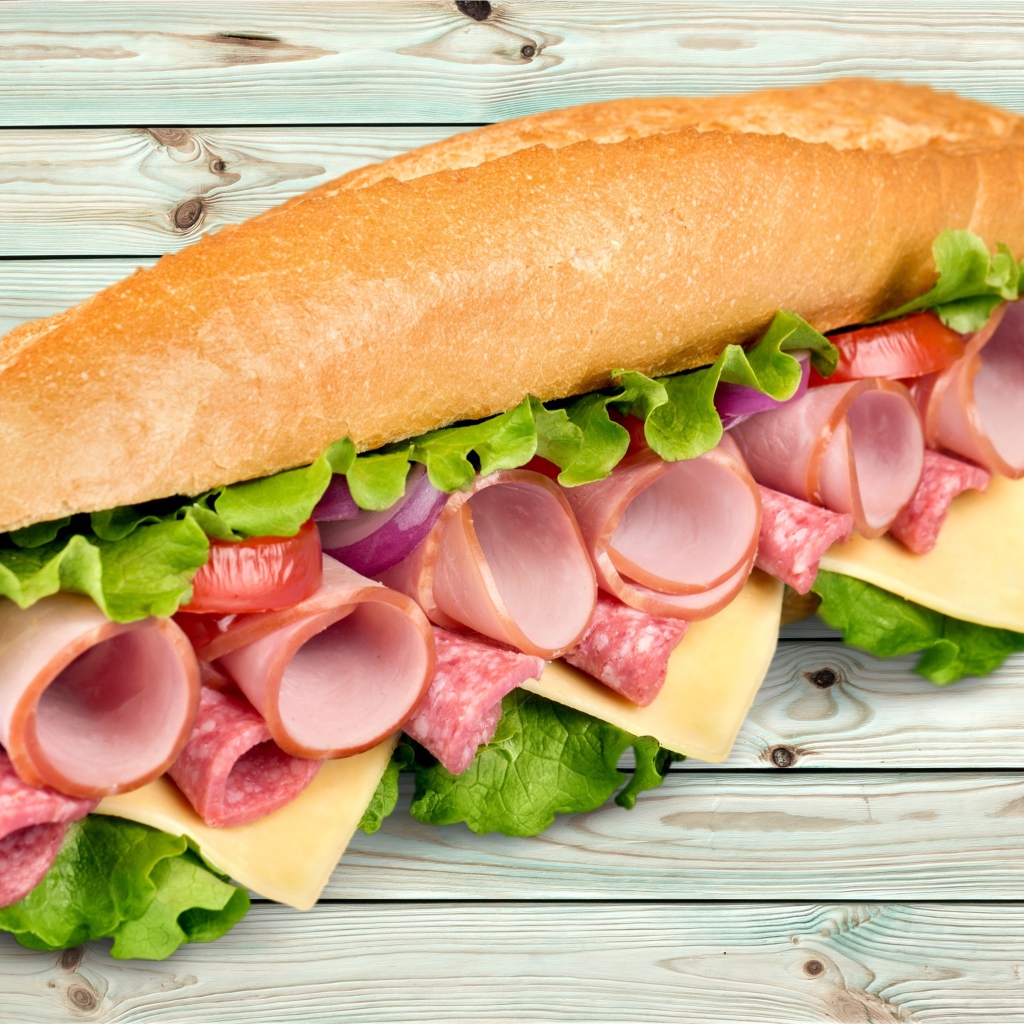 Большой бутерброд с колбасой, сыром и листьями салата