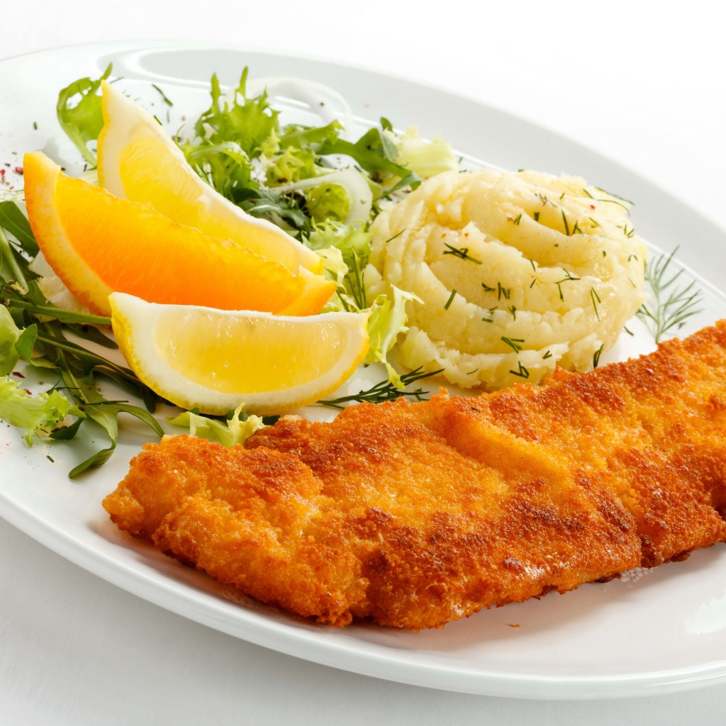 Картофельное пюре с мясом, кусочками апельсина и салатом на тарелке