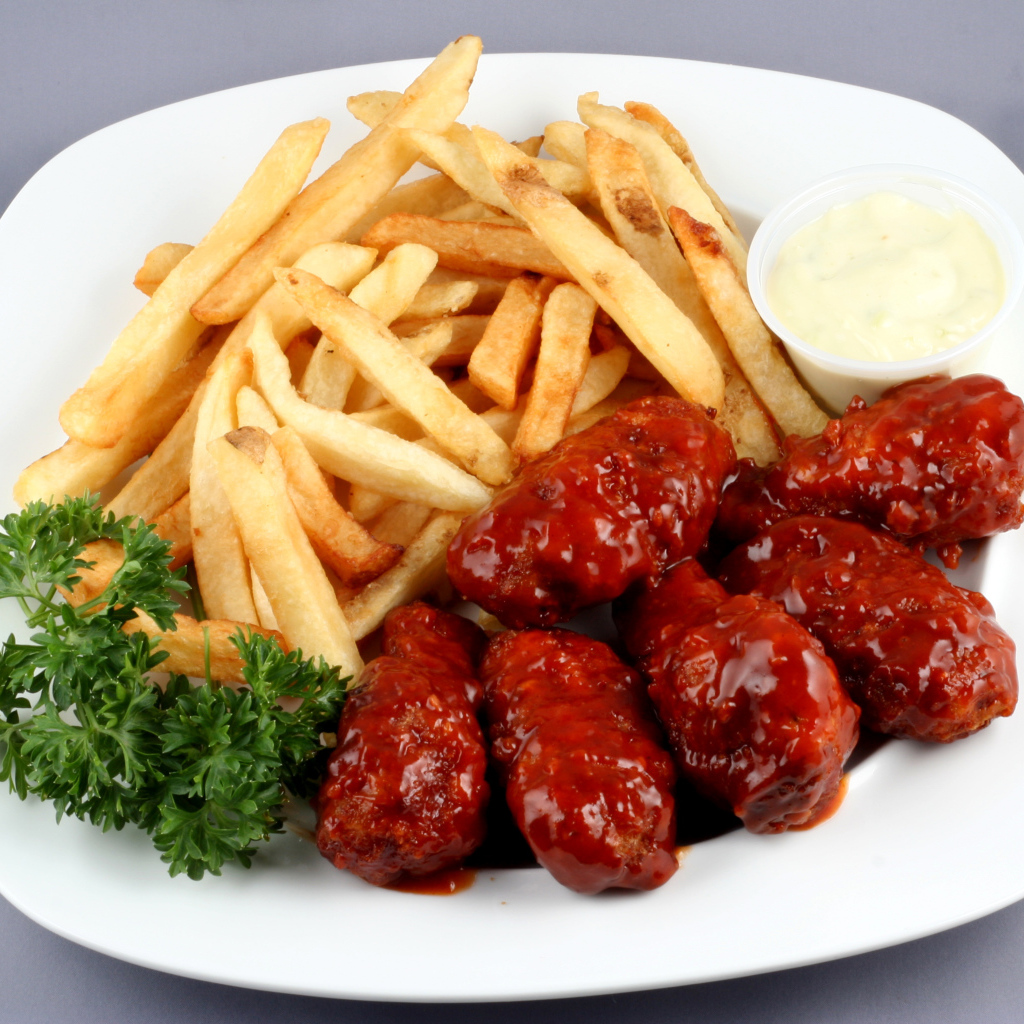 Тефтели в соусе с картофелем фри и петрушкой на тарелке