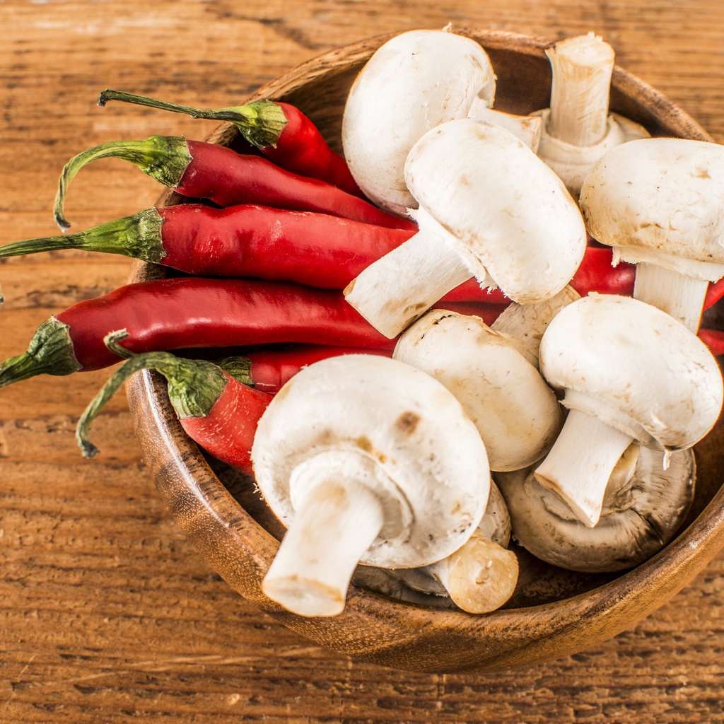 Грибы шампиньоны в деревянной миске с красным перцем