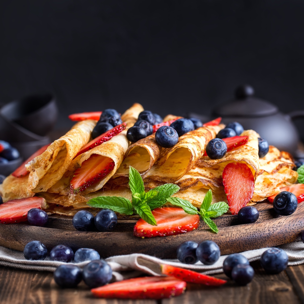 Блинчики с ягодами черники и клубники на столе