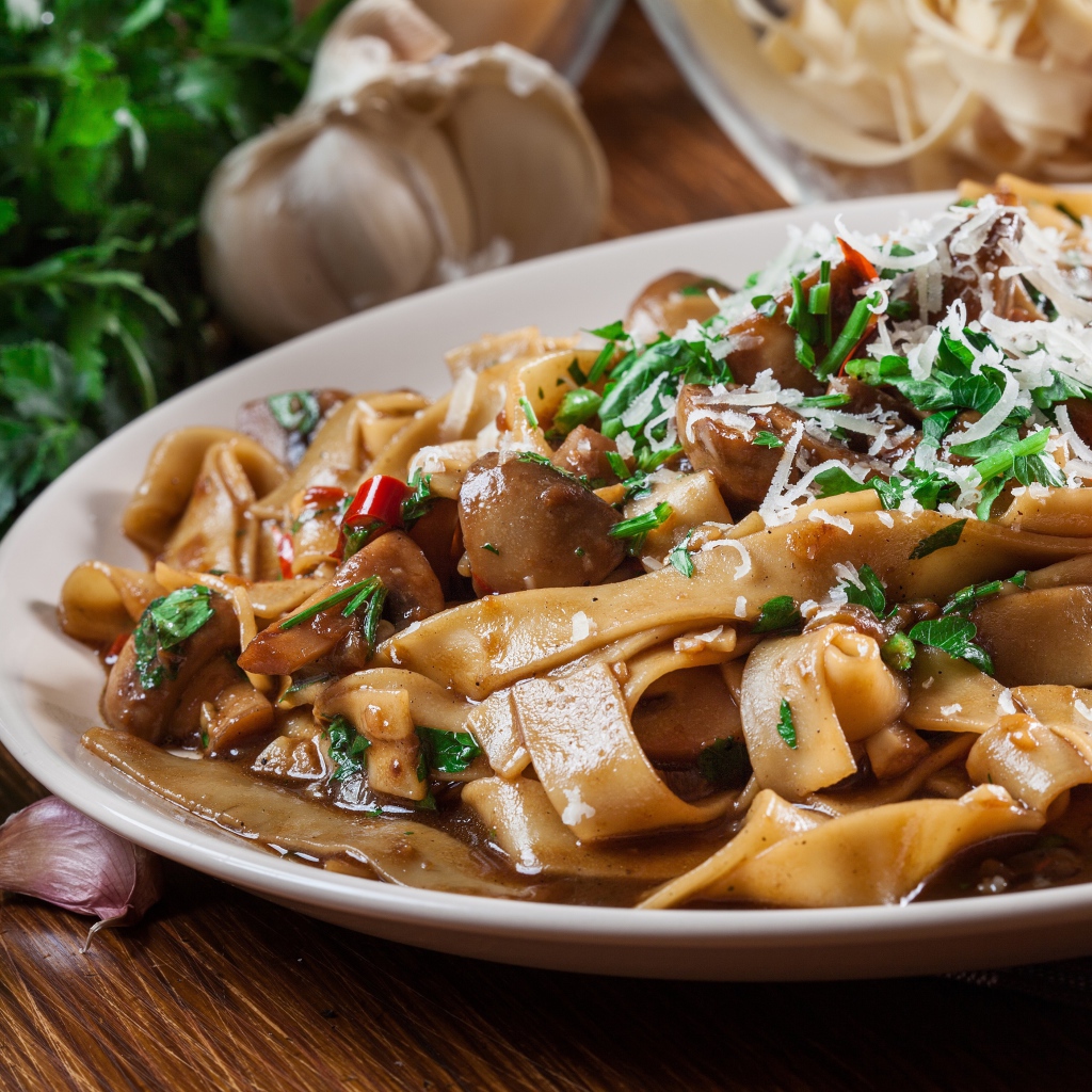 Паста с грибами, сыром и  зеленью на столе с чесноком 