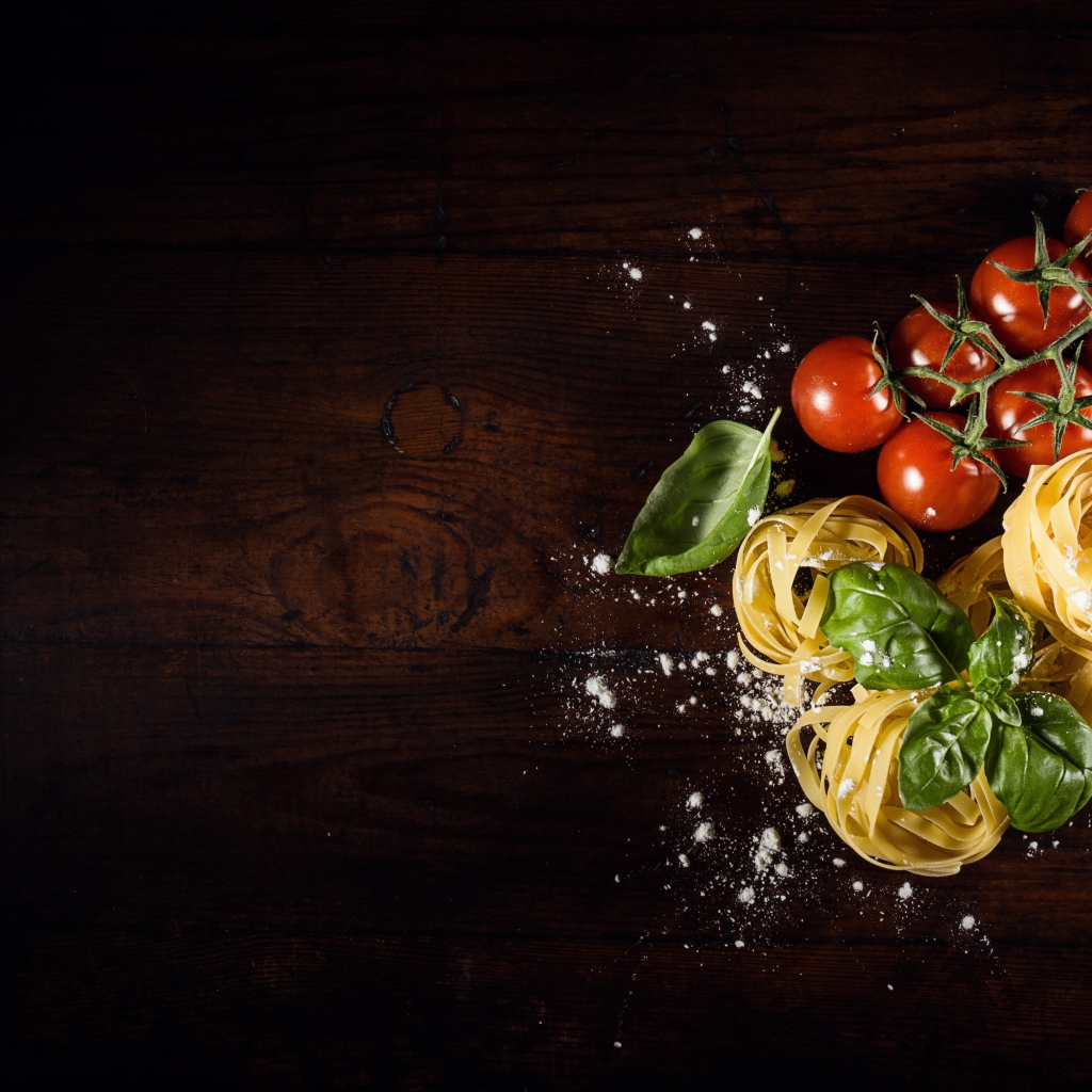 Паста с помидорами и листьями базилика на столе