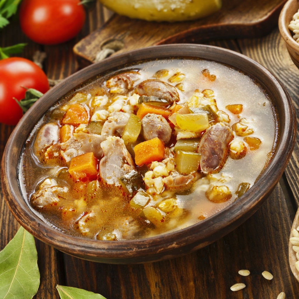 Перловый суп с сердечками на столе с помидорами 