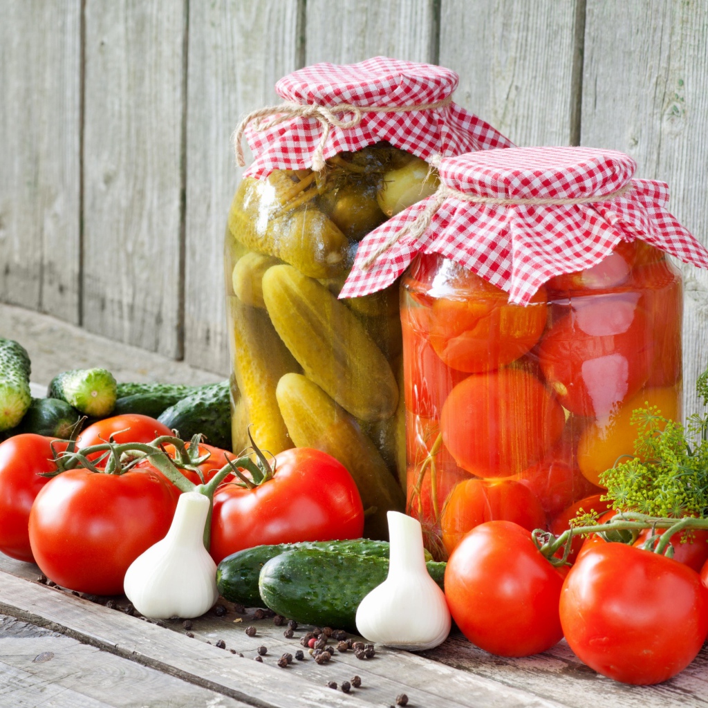 Соленья из огурцов и помидоров с овощами на столе