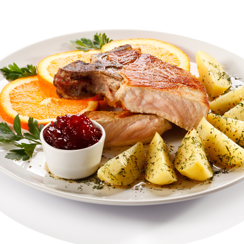 Картофель с мясом и кусочками апельсина на тарелке
