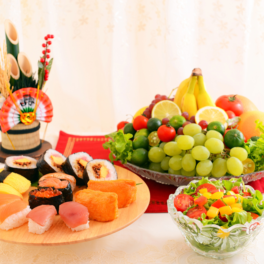 Роллы на столе с овощным салатом и фруктами 