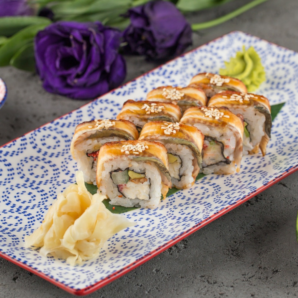 Роллы с авокадо и соевым соусом на столе с цветами 