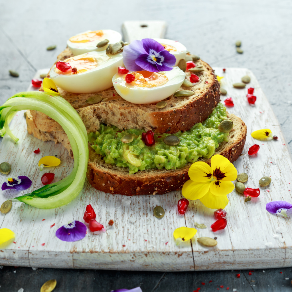 Сендвич с яйцом и цветами на доске