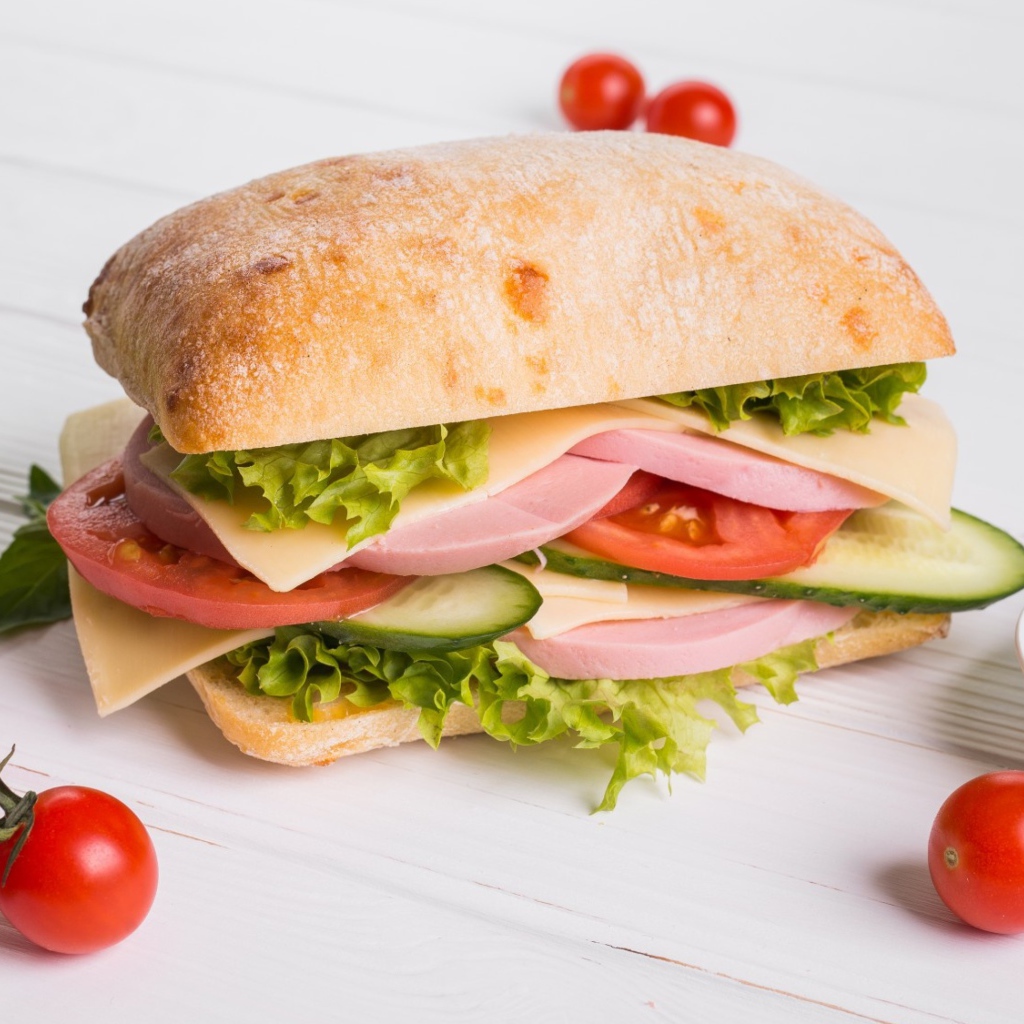 Сендвич с соусом и помидорами на столе 