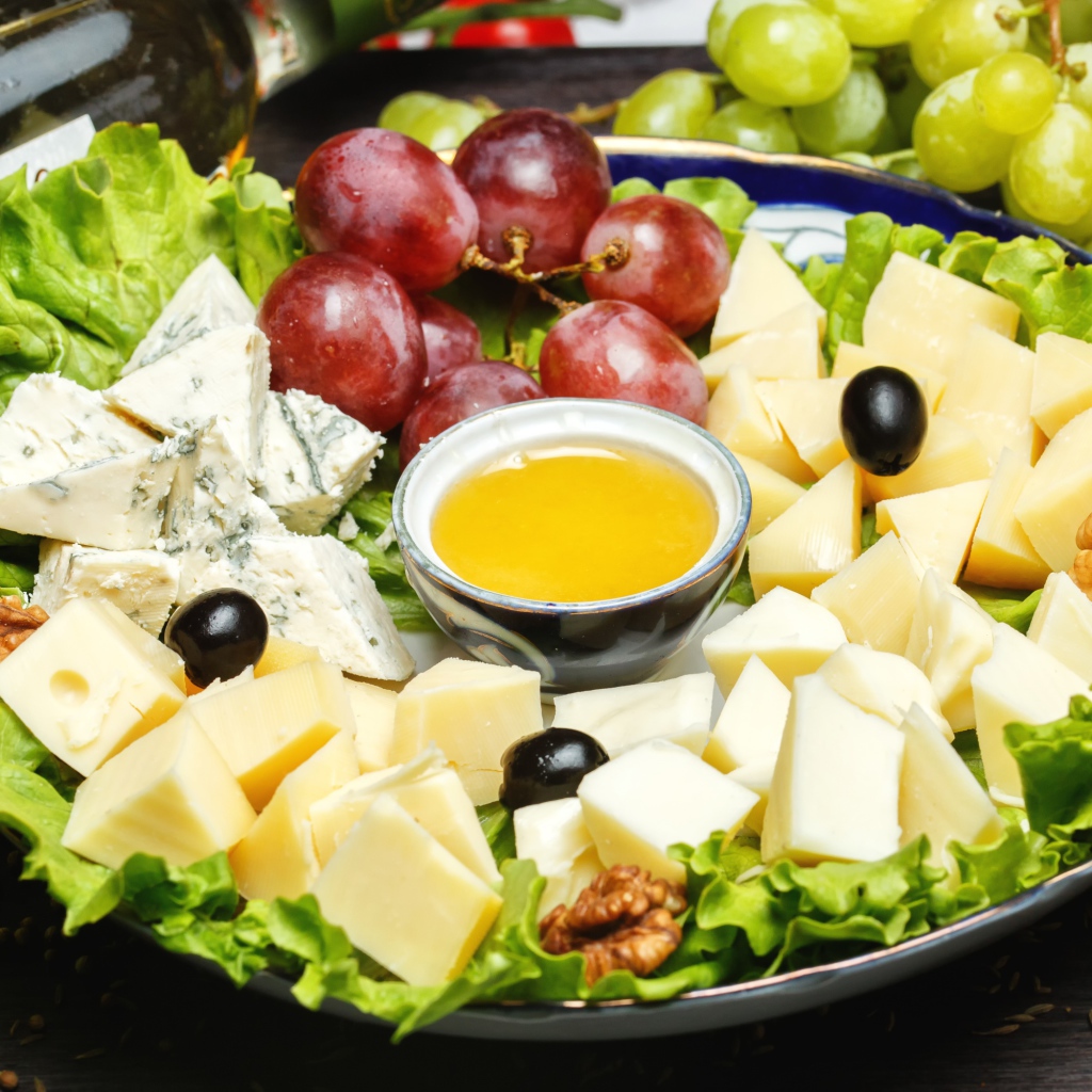 Нарезанный сыр на тарелке в виноградом 