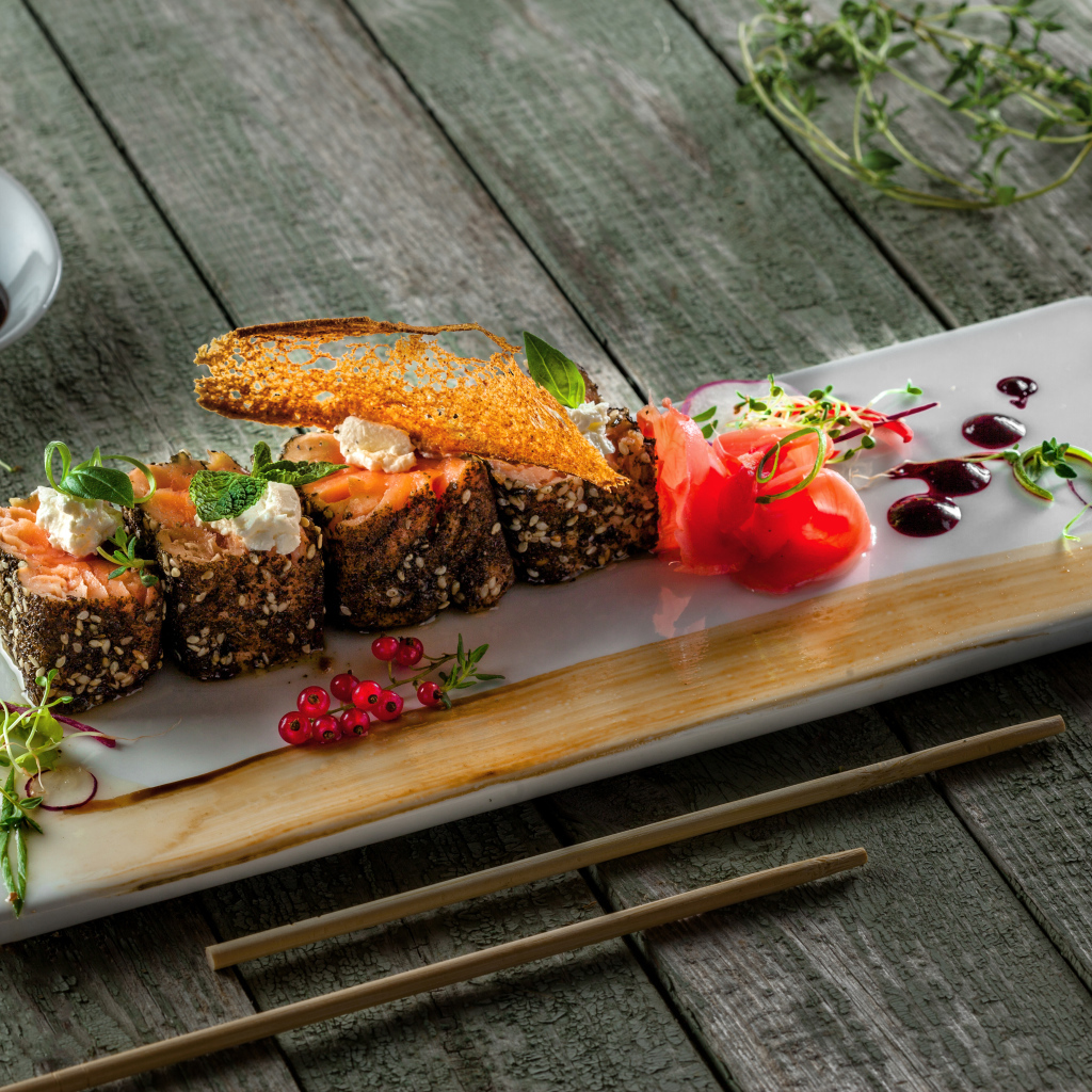 Суши на тарелке на деревянном столе с соусом